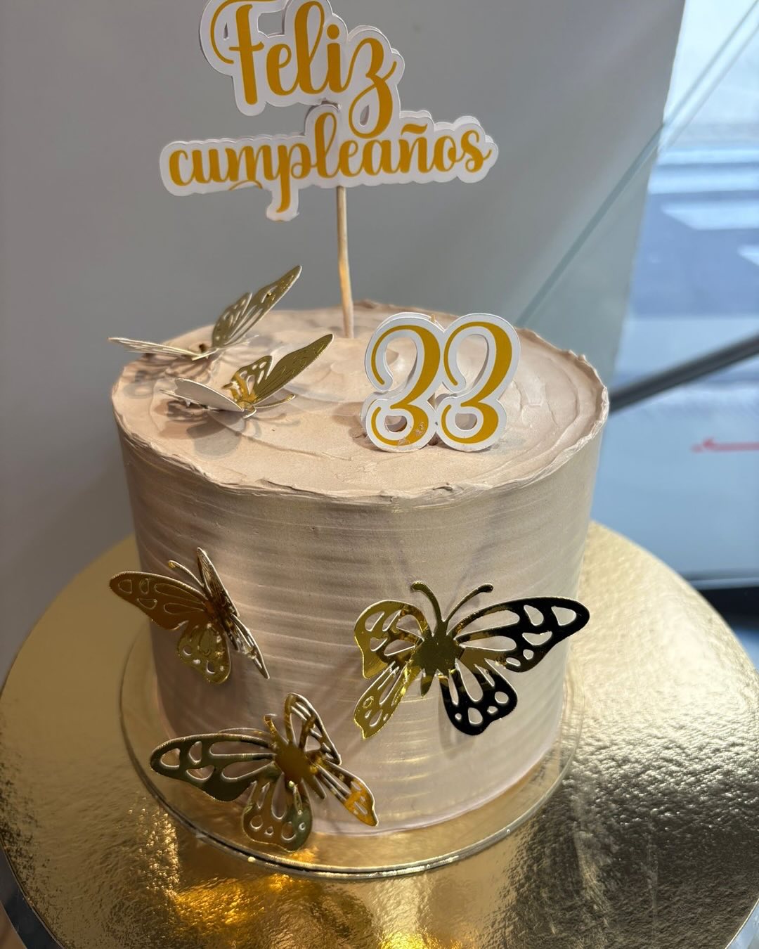 Pastel de cumpleaños de Aroma con velas de números y mariposas doradas